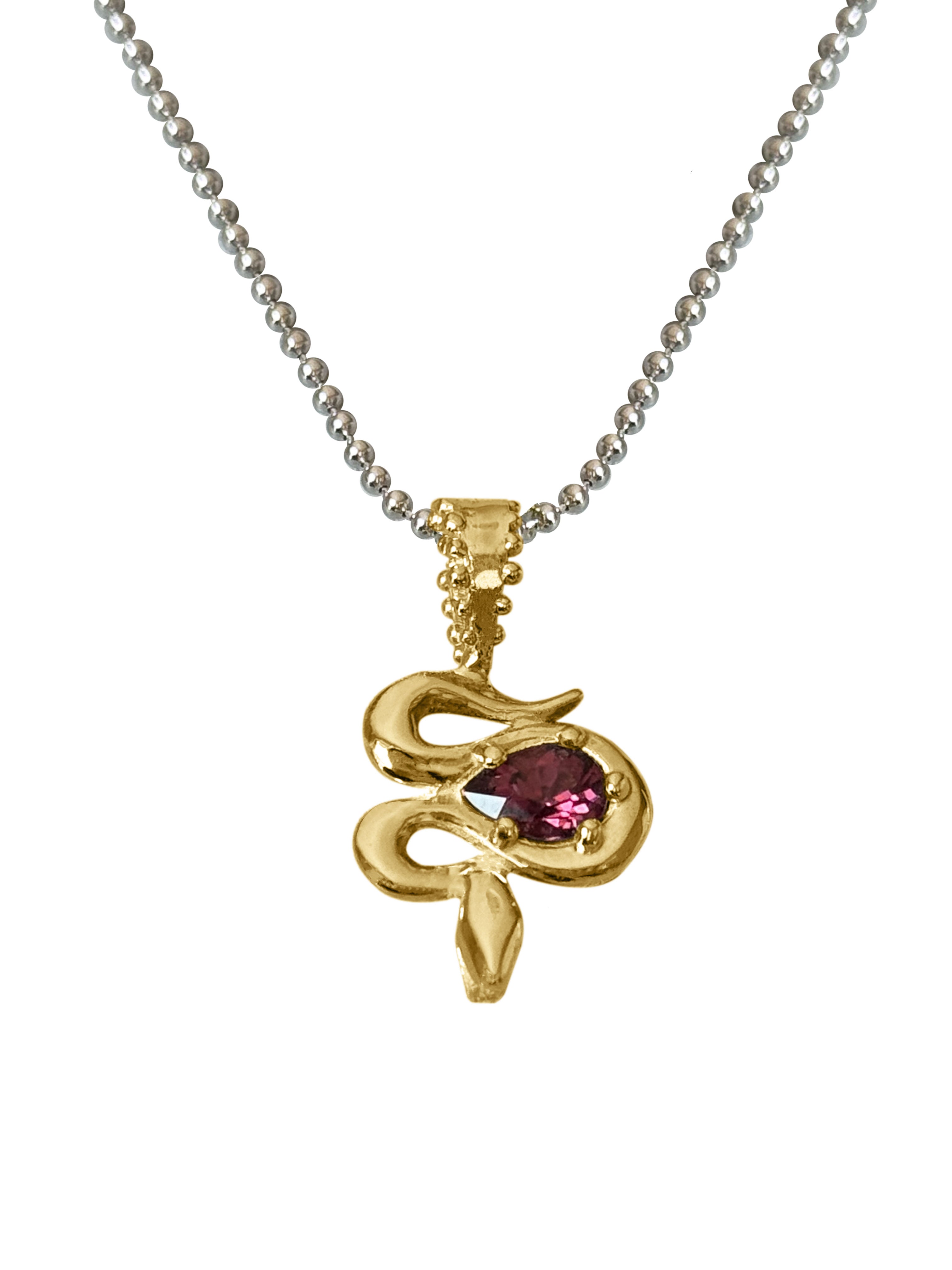 A close-up of the Bohème Serpent Charm in luminous 18 karat yellow Fairmined gold, coiled around a vivid raspberry Rhodolite Garnet. The serpent's intricate details catch the light, silhouetted against a white background.